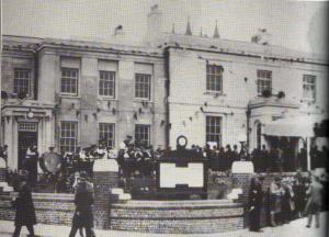 A black and white photograph showing the opening of the Manor House as Council Offices in the 1930s. The building is surrounded by people and covered in bunting.