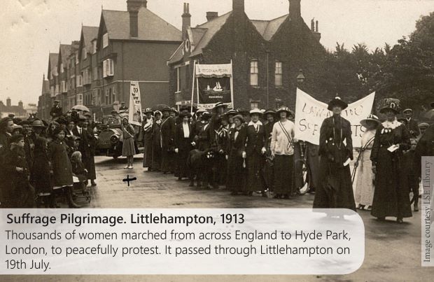 A black and white image of suffragette's lined up on a Littlehampton Street with Banners, 1913