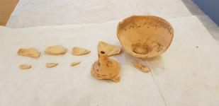 sherds of a fusiform bottle made of ceramic sit on white paper