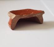 a broken cup base from a roman piece of samianware stands on a white background