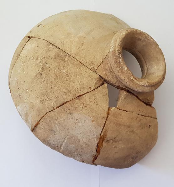the broken pieces of a large amphora have been haphazardly glued together. The vessel sits on a white background.