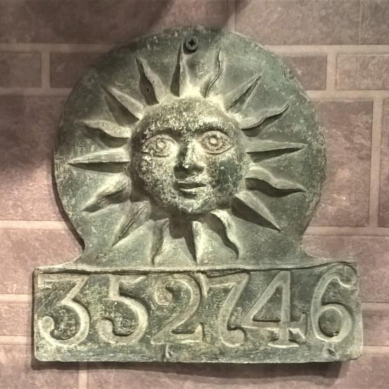 metal plaque with embossed sun and number 352746